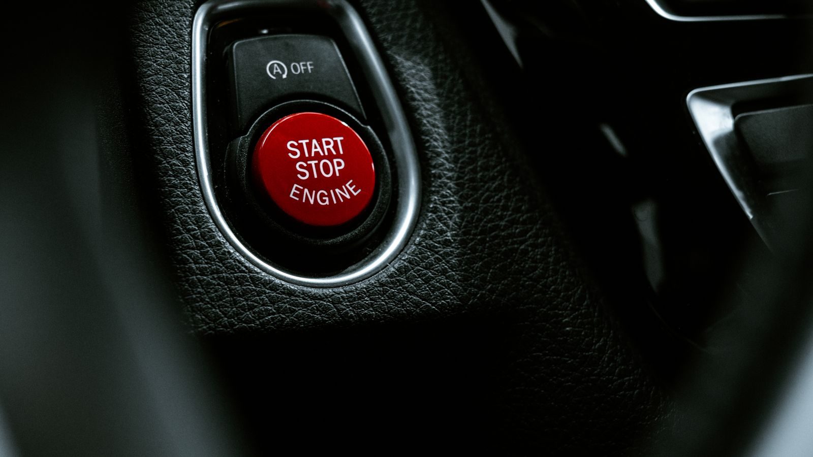 A car's engine start button on the dashboard