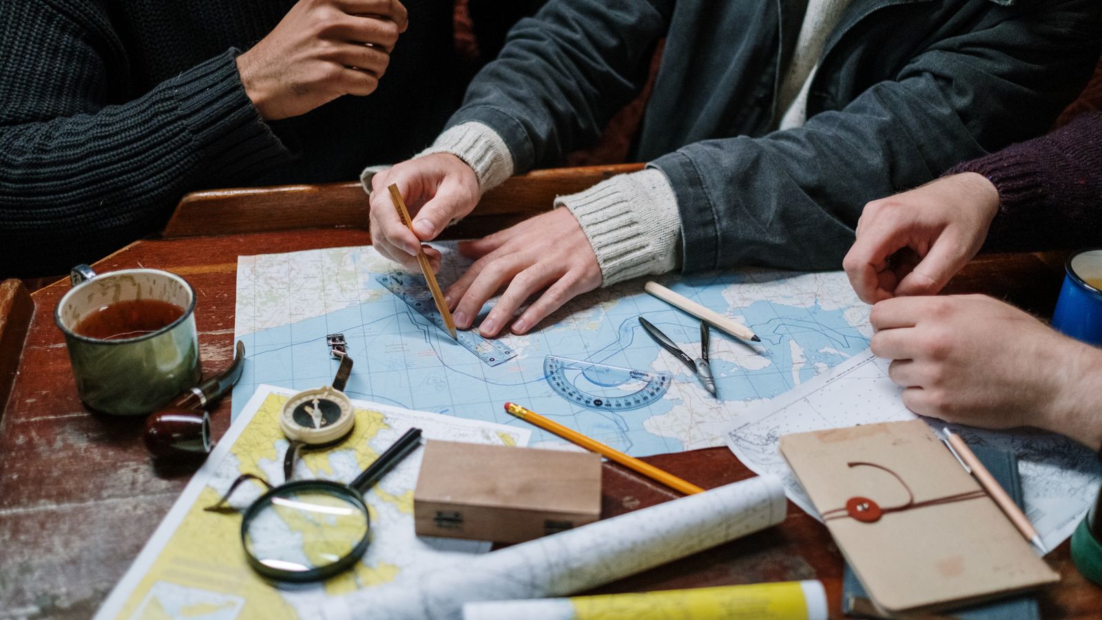 Hands marking a topographic map with a ruler and pencil