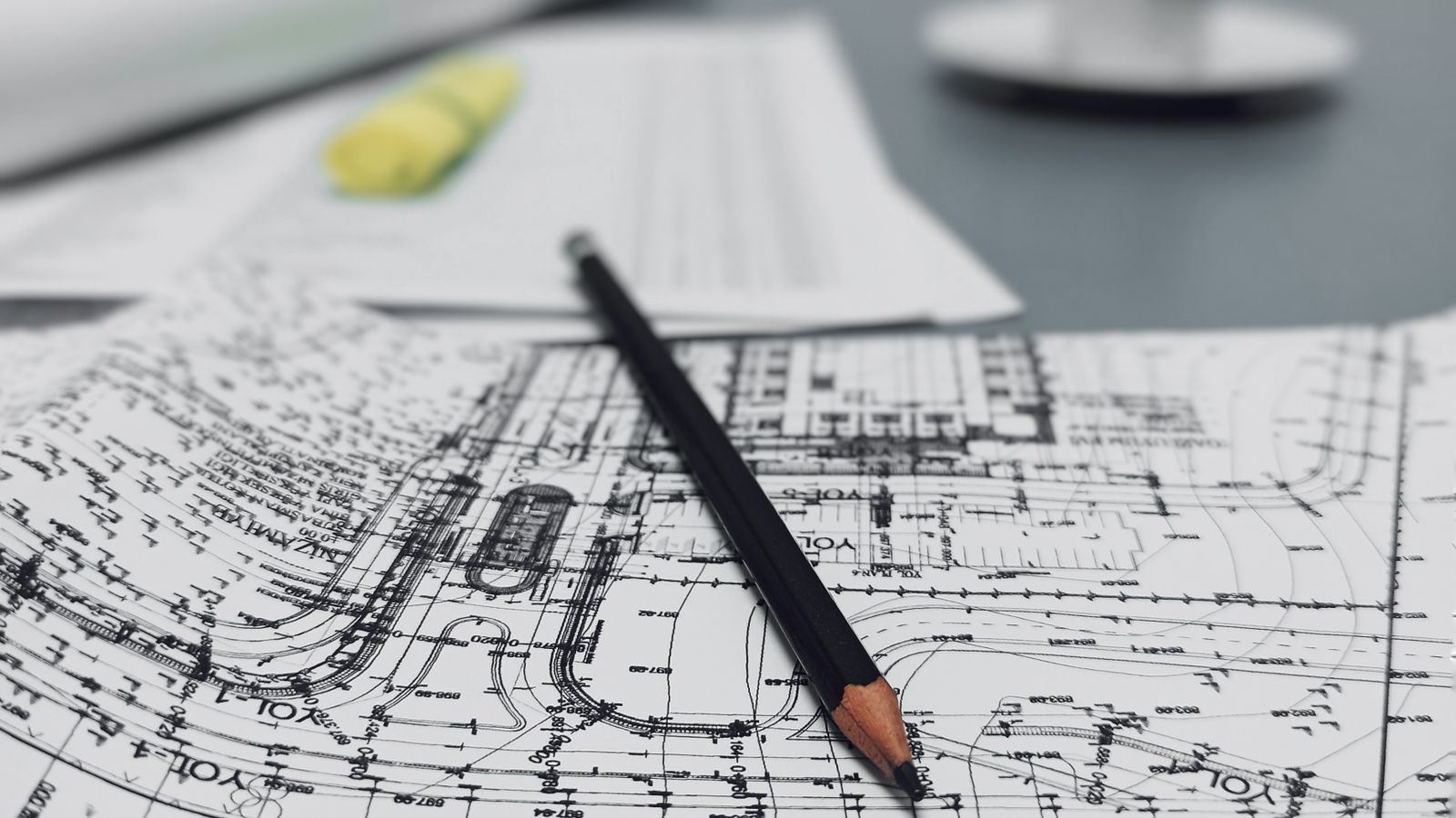 A site plan showing contour and elevation lines on a desk with a pencil