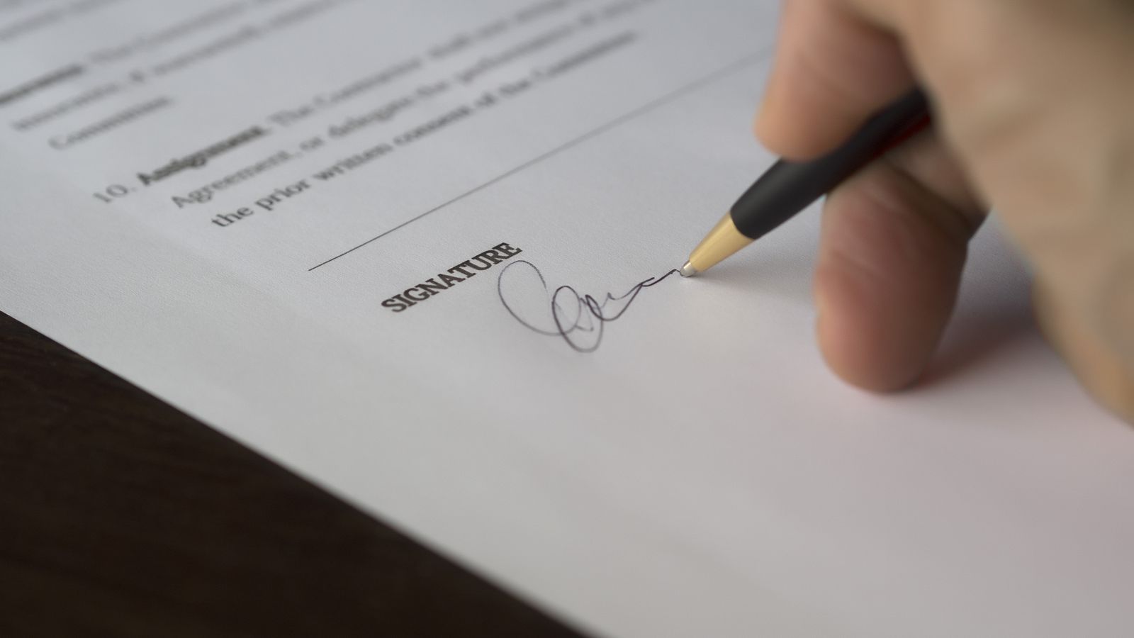 A hand signing the signature line of an insurance document