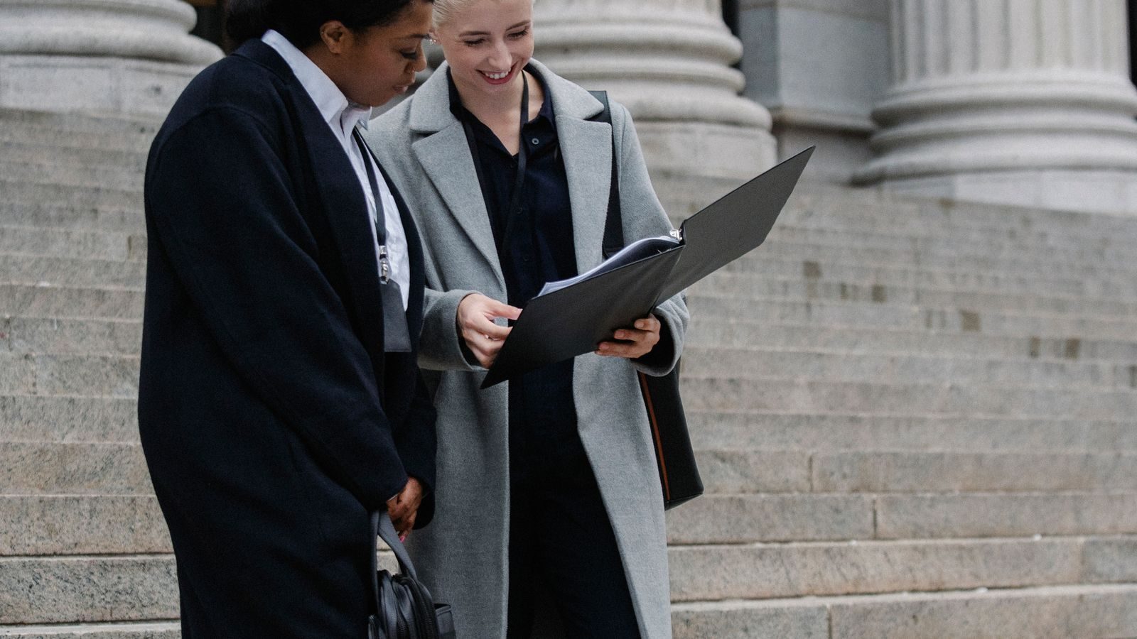Two people reviewing a folder of documents on courthouse steps